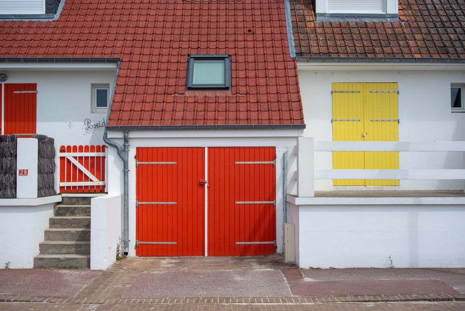 Painted house front with red and yellow doors and a tiled roof