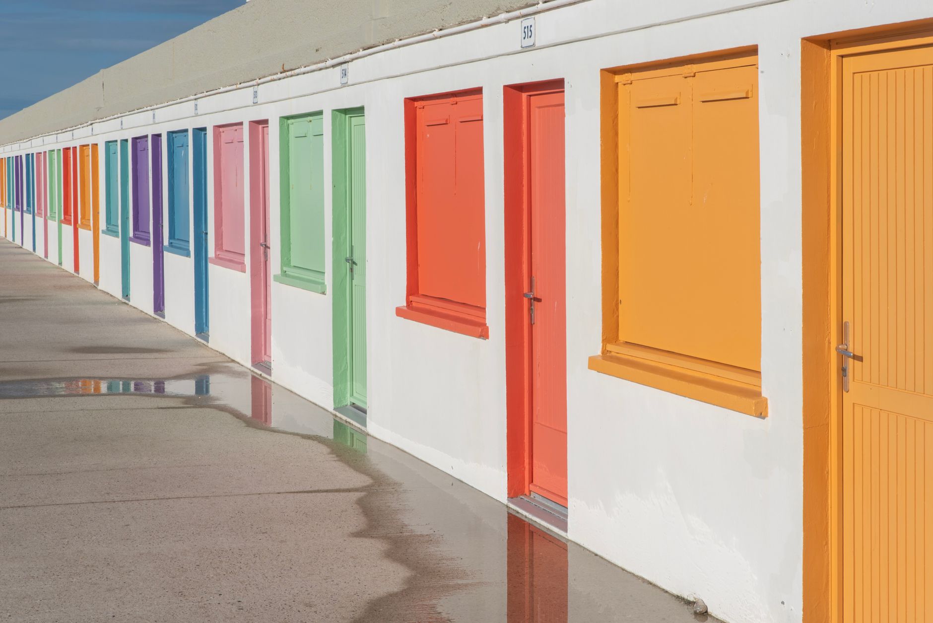 A line of colorful doors with bright paint reflecting sunlight. Ideal for vibrant lifestyle and architecture in Carlsbad, CA