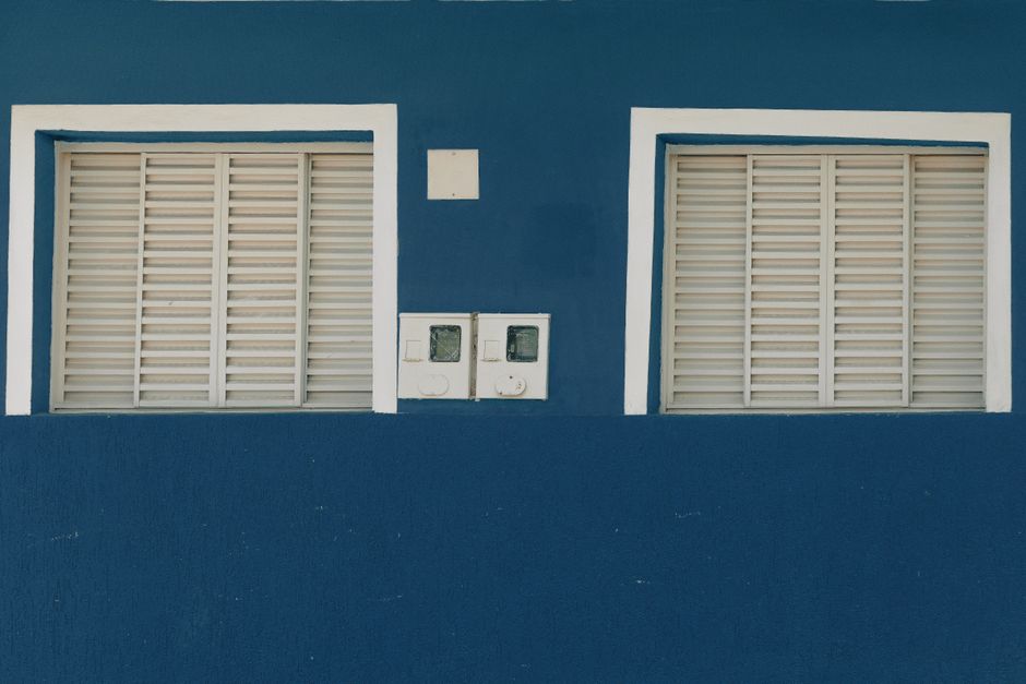Blue painted wall with two white shuttered windows