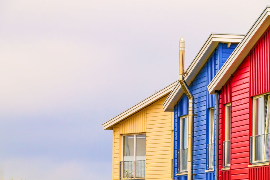 Red, blue and yellow painted houses under a clear sky